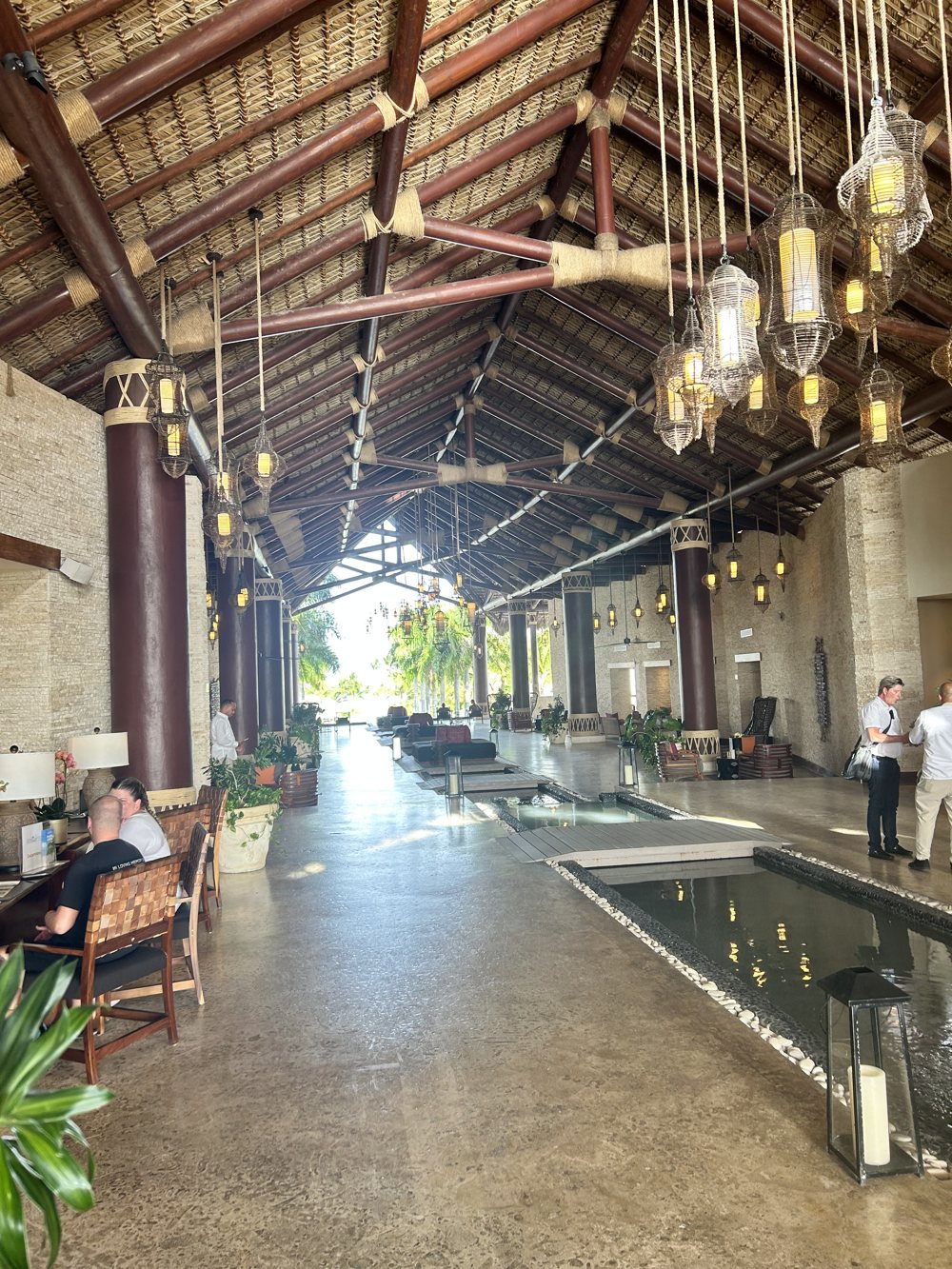 The open-air lobby walkway with hanging lanterns and a reflecting pool