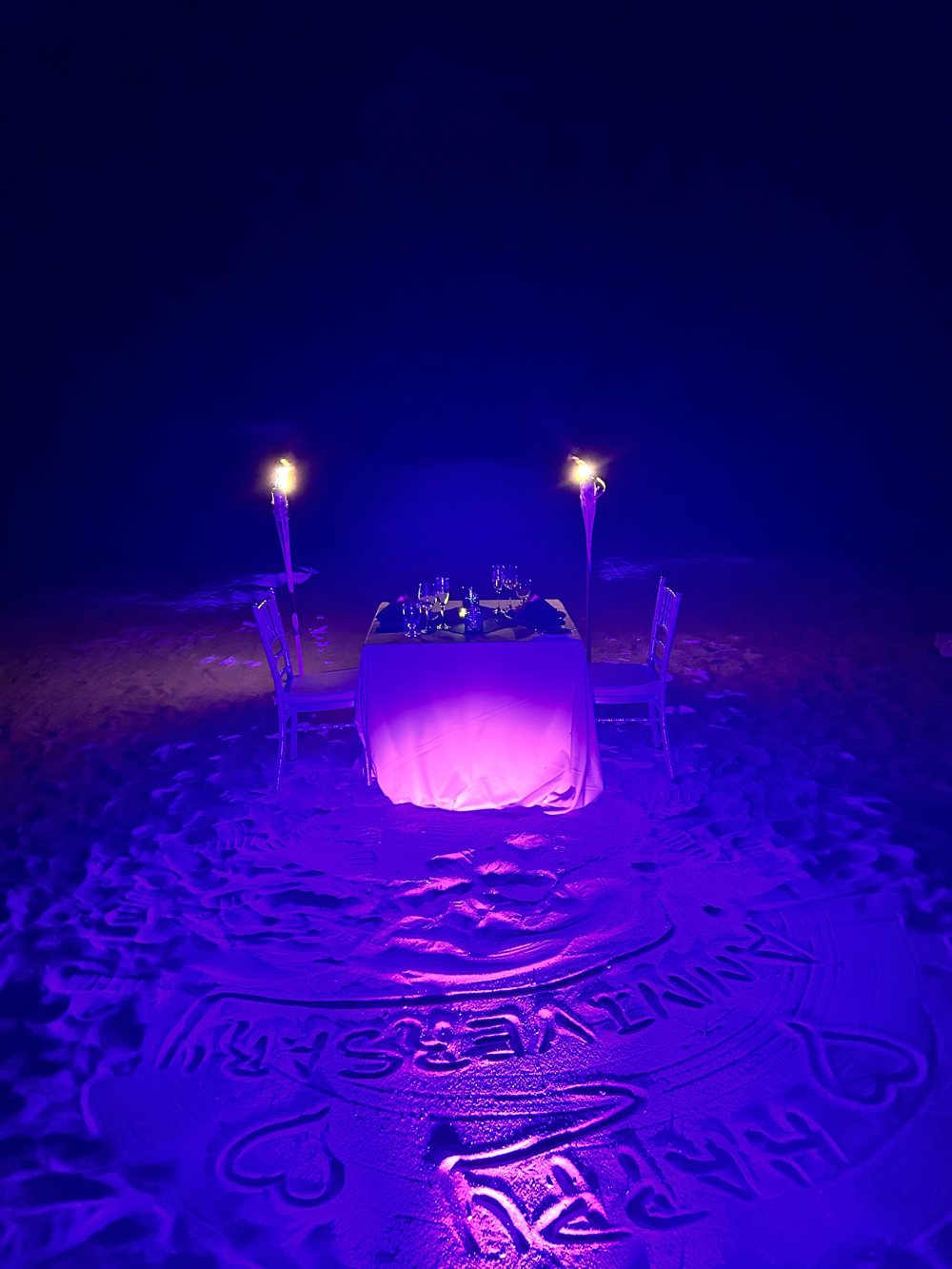 A private candlelit dinner set up on the beach at night