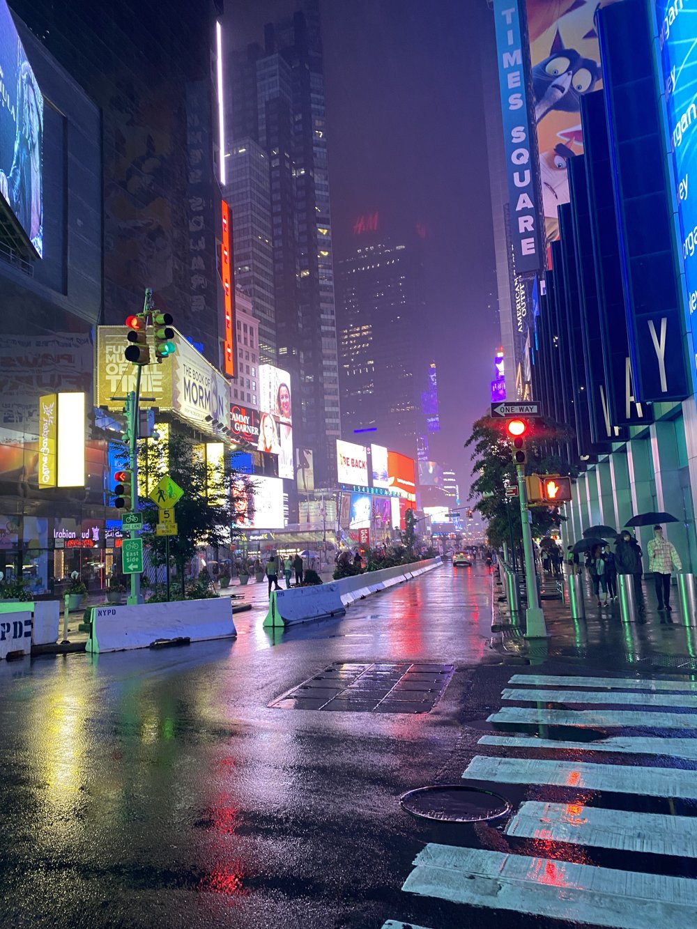 Times Square at night, neon billboards reflected on wet pavement
