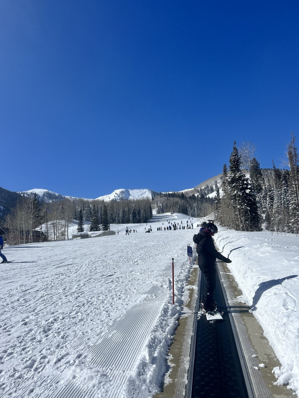 The beginner magic-carpet lift with the snowy mountain behind it