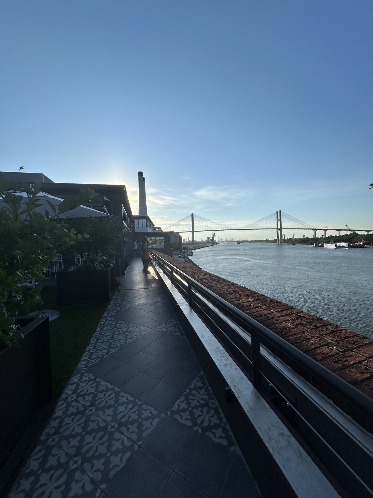 The Savannah riverfront walkway at dusk, the Talmadge Memorial Bridge lit in the distance over the water